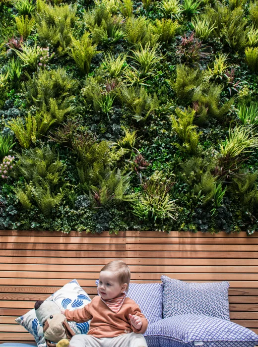Residential Backyard in front of Vertical Garden and baby playing with toys in front of pillows. 