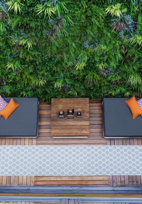 Outdoor patio with large vertical garden with lush foliage and lounge with pillows