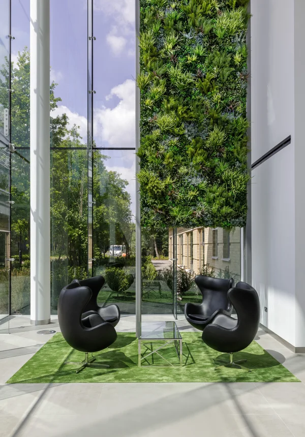 Commercial lobby with beautiful vertical green wall by waiting area with four black chairs