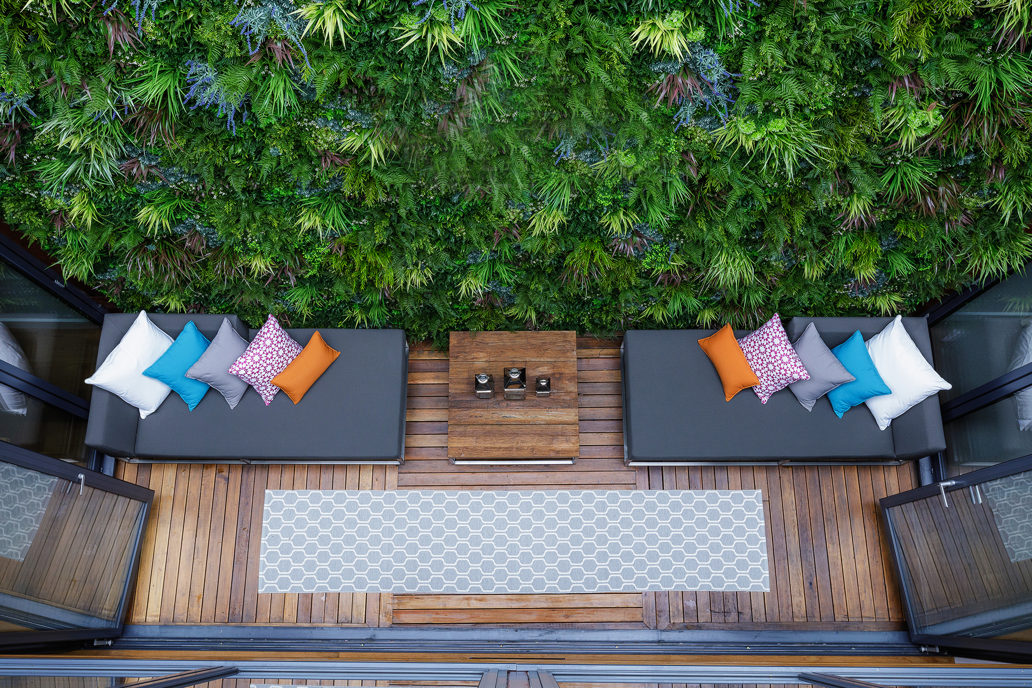 Outdoor patio with large vertical garden with lush foliage and lounge with pillows
